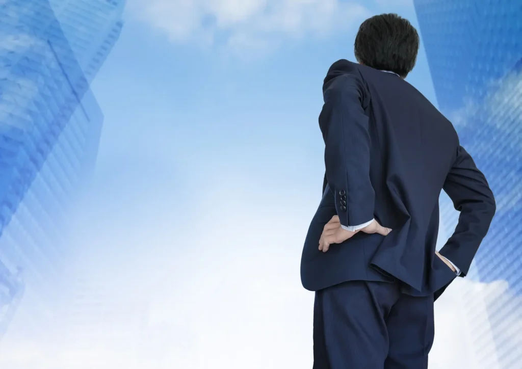 ビル街を見上げるビジネスマンの後ろ姿